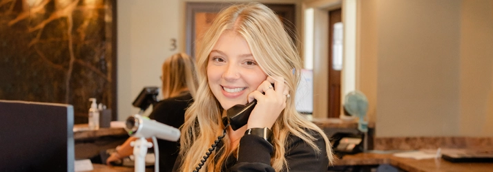 Chiropractic Dalton GA Staff Member On The Phone Contact Us Staff Member On The Phone And Smiling At Front Desk