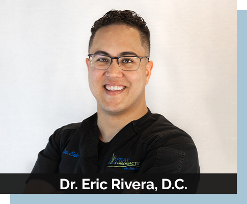 Chiropractor Eric Rivera Smiling In Front Of White Background With Blue Backdrop
