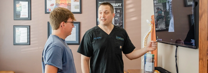 Chiropractor Jason McRae Pointing To Screen With Patient