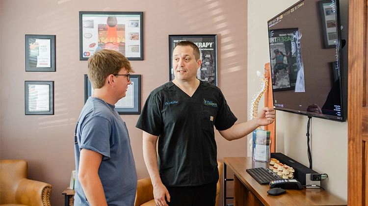 Chiropractor Jason McRae Pointing To XRay With Patient